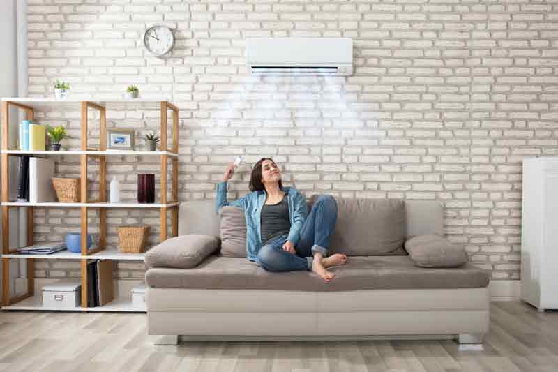 Ductless heating and air conditioning installation in Santee ca with woman enjoying comfort on her couch.